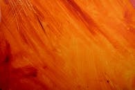 Close-up of an abstract painting with vibrant orange and yellow hues.